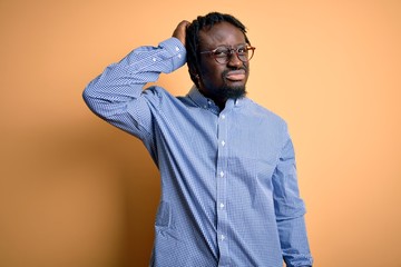 Poster - Young handsome african american man wearing shirt and glasses over yellow background confuse and wondering about question. Uncertain with doubt, thinking with hand on head. Pensive concept.