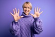 © Krakenimages.com - Young blonde woman with short hair wearing winter turtleneck sweater over purple background showing and pointing up with fingers number ten while smiling confident and happy.