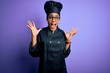 © Krakenimages.com - Young african american chef girl wearing cooker uniform and hat over purple background celebrating crazy and amazed for success with arms raised and open eyes screaming excited. Winner concept