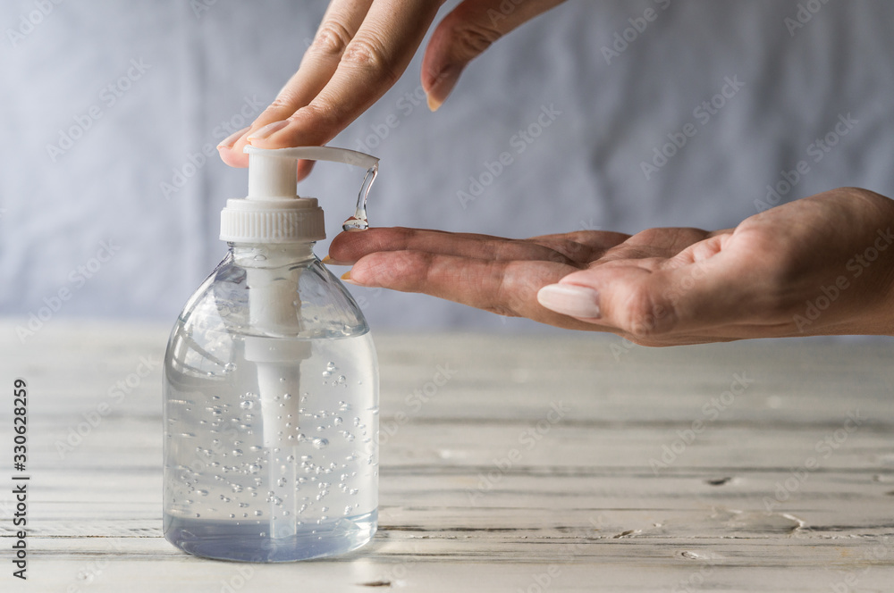 Young woman using hand sanitizer gel with liquid alcohol disinfectant for prevention of coronavirus and other pandemic and epidemic diseases - obrazy, fototapety, plakaty 