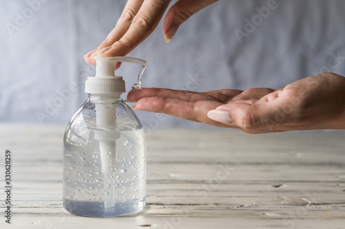 Cuadros en Lienzo Young woman using hand sanitizer gel with liquid alcohol disinfectant for preven