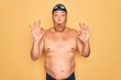 © Krakenimages.com - Middle age senior grey-haired swimmer man wearing swimsuit, cap and goggles looking surprised and shocked doing ok approval symbol with fingers. Crazy expression