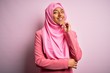 © Krakenimages.com - Young African American afro woman wearing muslim hijab over isolated pink background looking confident at the camera smiling with crossed arms and hand raised on chin. Thinking positive.