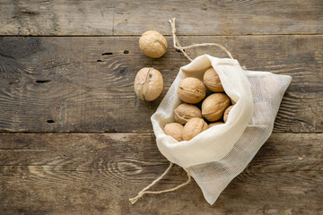 Wall Mural - Walnuts in cotton bag on a wooden background