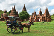 Horse drawn carriage tourists is driving along in front of the ancient temple of Bagan, Myanmar. 