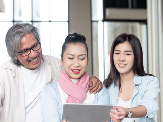 Happy asian family Father, mother and daughter using Digital tablet in home. Technology Communication and lifestyle