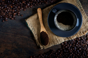 Wall Mural - A cup of black coffee and coffee beans roasted on an old wooden table