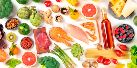 Food panorama, a flat lay of many different products, with meat, fish, chicken and shrimps, vegetables and fruits, wine and cheese, shot from the top on a white background