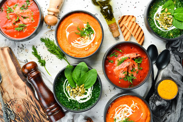 Set of colored tasty soups on white wooden background. Spinach, tomato and carrot soup. Healthy food.