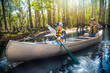 © Brocreative - Adventuresome Father and son canoeing together on a beautiful river in a thick forest. Family vacations and new experiences. Smiling and having fun together in nature