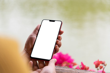 Wall Mural - Close-up of female holding blank smartphone on park pond background