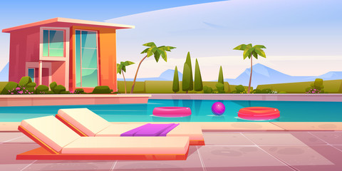 House and swimming pool with deck chairs on poolside and balls in water. Vector cartoon summer landscape with villa, basin on lawn, palms and mountains on background