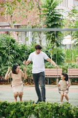 Wall Mural - Happy young father spending time with his daughter and wife in park