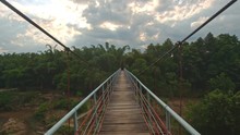 Suspension Bridge Over River Against Cloudy Sky At Sunset