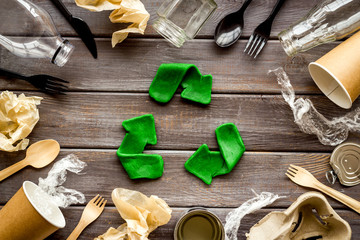 Wall Mural - Recycle concept. Green arrows icon among waste on dark wooden background top-down