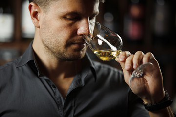 Wall Mural - Bokal of white wine on background, male sommelier appreciating drink