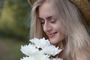 Summer portrait of a young blonde woman with flowers, close-up, chosen focus