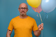 © Viktor Koldunov - Displeased upset adult looking mournful and unhappy, does not want to get old, standing with colorful balloons in his hands