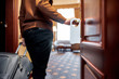 © Svitlana - Make Yourself at Home. Cropped shot of middle-aged businessman in casual wear with suitcase entering his room. A door with a sign.