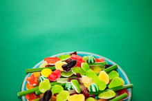 Plate With Colored Jelly Sweets In The Middle Of A Green Background, Clouse Up Shot. Photo Made With Love For Your St.Patrick's Day Design.
