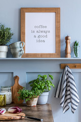 Interior design of kitchen space with mock up photo frame, wooden table, herbs, vegetables, food and kitchen accessories in modern home decor.