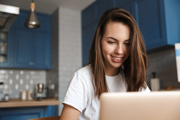 Wall Mural - Happy woman indoors at home using laptop computer.