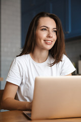 Canvas Print - Happy woman indoors at home using laptop computer.