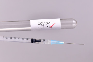 Wall Mural - syringe and medical test tube sample for coronavirus with label covid-19 in blurry background, conce