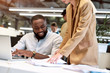 © Svitlana - Great job. Young afro american cheerful man discussing project reports with his colleague while working together in the modern office