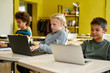 © Svitlana - Together Everyone Accomplishes More. Portrait of caucasian schoolgirl looking at the screen of the laptop together with other pupils during a lesson in modern smart school