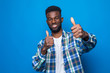 African american man doing happy thumbs up gesture with hand standing over isolated blue background