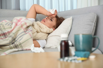 Wall Mural - Sick woman lying on sofa at home. Influenza virus