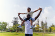 Happy African American father and son piggyback in outdoor park. Fatherhood and family lifestyle concept - with copy space