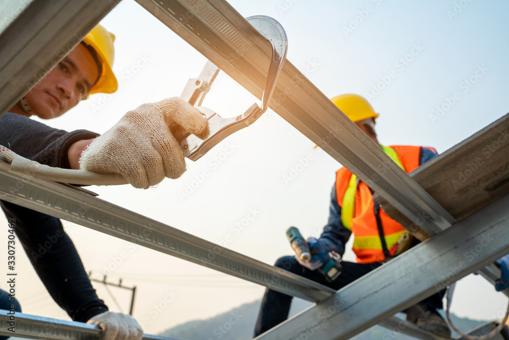 Construction worker wearing safety harness belt during working at high place and installing concrete roof tile on top of the new roof,Concept of residential building under construction. - obrazy, fototapety, plakaty 