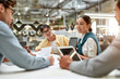 © Svitlana - Work is easier with technologies. Young asian woman showing tablet to her colleagues and discussing something while working together in the modern office