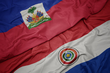 waving colorful flag of paraguay and national flag of haiti.