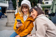 © Adrian - Two caucasian girls using a smartphone.