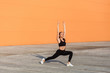 © khosrork - Slim fit girl in tight sportswear, black pants and top, practicing yoga, standing in Virabhadrasana i warrior pose and meditating, doing stretching exercise. Health care, sport activity outdoor