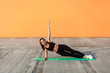 © khosrork - Athletic beautiful girl in tight sportswear, black pants and top, practicing yoga, doing Vasisthasana side plank pose with one hand, training muscles and strength. Health care, sport activity outdoor