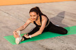 © khosrork - Smiling beautiful athletic girl in tight sportswear, black pants and top, practicing yoga, touching toes stretching muscles and warming up, training flexibility. Health care, sport activity outdoor