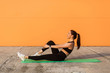 © khosrork - Happy smiling athletic girl in tight sportswear, black pants and top, doing aerobics gymnastics, stretching legs on yoga mat, training abs muscular and flexibility. Health care, sport activity outdoor