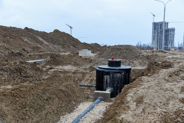 Laying drain pipes and concrete manholes for stormwater system. Connecting a trench drain to a concrete manhole structure at construction site. Construct stormwater and underground utilities