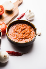 Wall Mural - onion tomato masala or puree for indian gravy, served in a bowl with raw tamatar, pays and lehsun and red chilli, selective focus