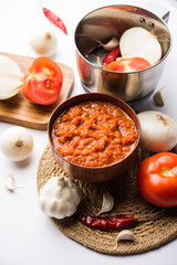 Wall Mural - onion tomato masala or puree for indian gravy, served in a bowl with raw tamatar, pays and lehsun and red chilli, selective focus