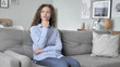 © stockbakers - Pensive Curly Hair Woman Thinking while Sitting on Couch