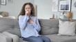 © stockbakers - Sick Young Curly Hair Woman Coughing while Sitting on Couch