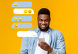 Millenial African American guy using smartphone for chat communication on orange background, empty space