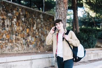 Young hispanic man using mobile phone while walking outdoors