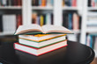 © Peter - A stack of books on a black table. Library in the background. Stack of books close up.