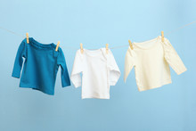 Baby Clothes On A Rope On A Colored Background. The Concept Of Washing Baby Clothes.